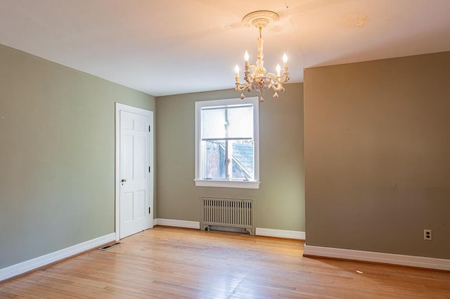 spare room featuring baseboards, radiator heating unit, a chandelier, and visible vents