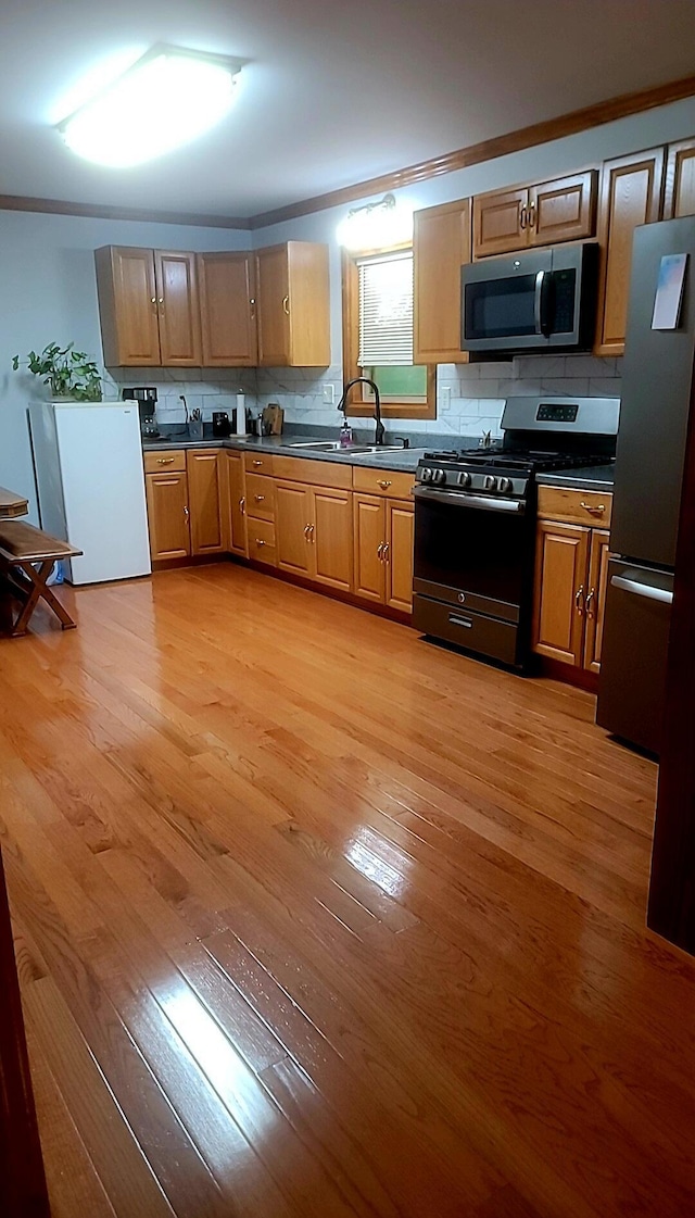 278 John Dr, Burnside, KY 42519 - kitchen with crown molding, light wood-type flooring, decorative backsplash, appliances with stainless steel finishes, and a sink