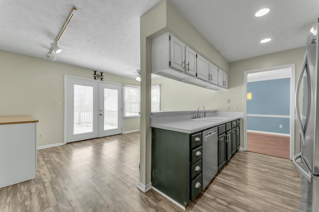 kitchen featuring a sink, a textured ceiling, french doors, appliances with stainless steel finishes, and light countertops