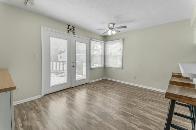 interior space featuring french doors, baseboards, a ceiling fan, and wood finished floors
