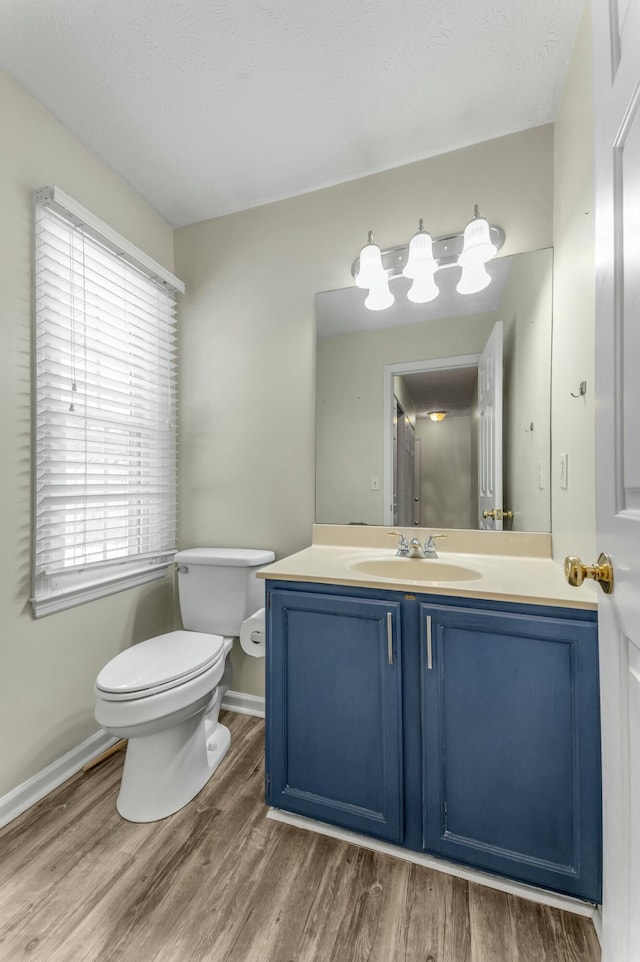 bathroom with baseboards, toilet, wood finished floors, and vanity