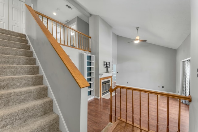 stairs featuring baseboards, ceiling fan, beamed ceiling, wood finished floors, and high vaulted ceiling