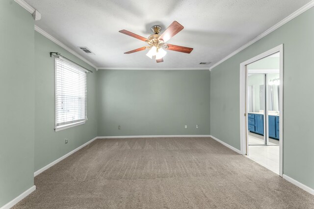 spare room with visible vents, carpet, a ceiling fan, and crown molding