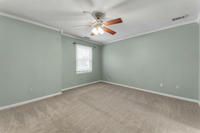 carpeted spare room featuring visible vents, baseboards, ceiling fan, and crown molding