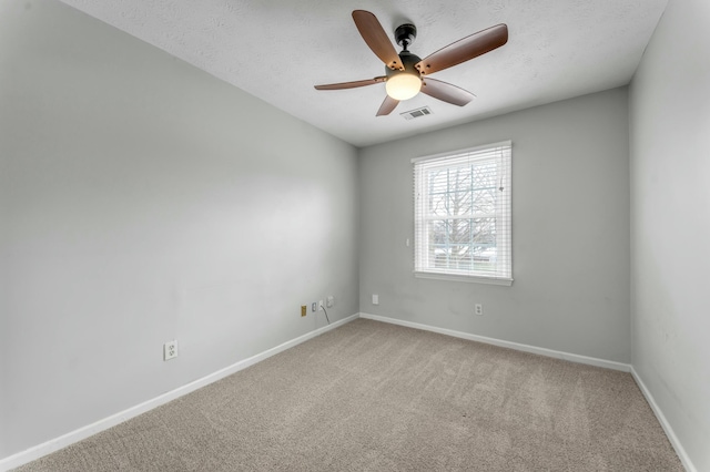 carpeted spare room featuring visible vents, baseboards, a textured ceiling, and a ceiling fan
