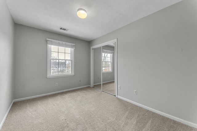 unfurnished bedroom with a closet, visible vents, carpet flooring, and baseboards