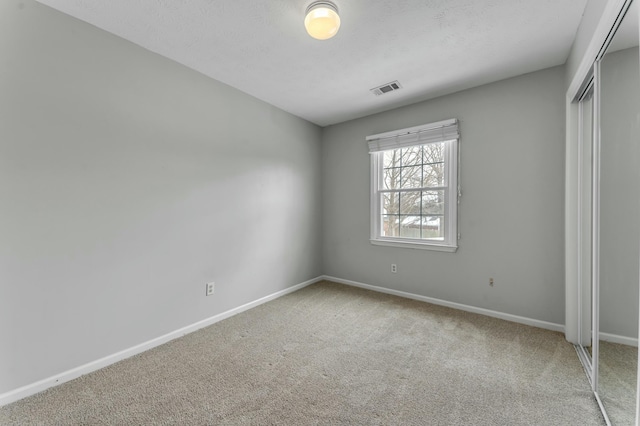 unfurnished bedroom with visible vents, baseboards, carpet, a closet, and a textured ceiling