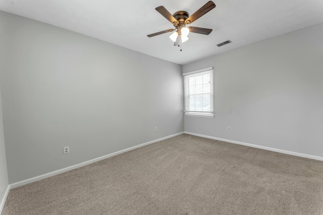 carpeted spare room featuring baseboards, visible vents, and ceiling fan