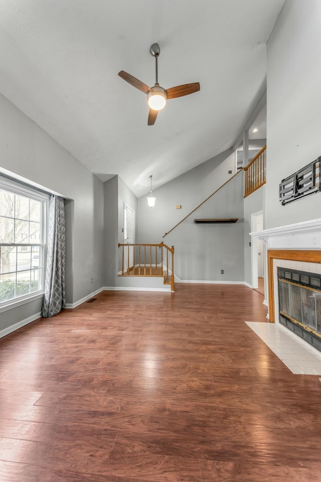 unfurnished living room featuring wood finished floors, a ceiling fan, baseboards, and a tile fireplace