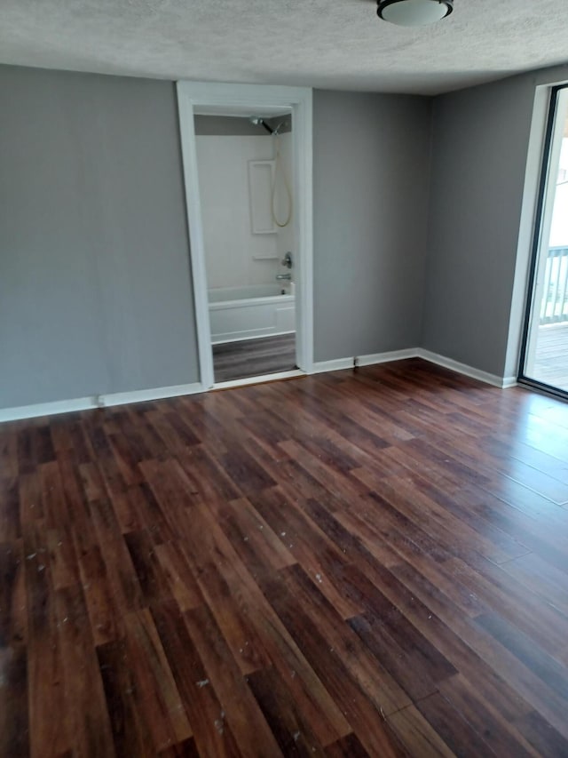 empty room with baseboards, a textured ceiling, and dark wood-style flooring