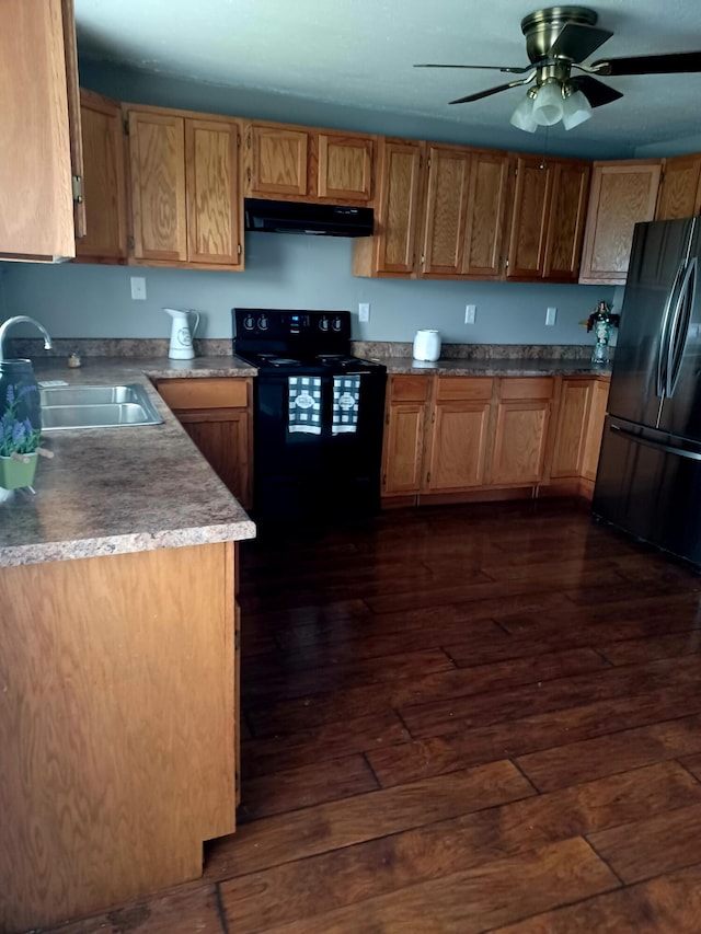 kitchen with a sink, black appliances, dark wood-style flooring, and under cabinet range hood