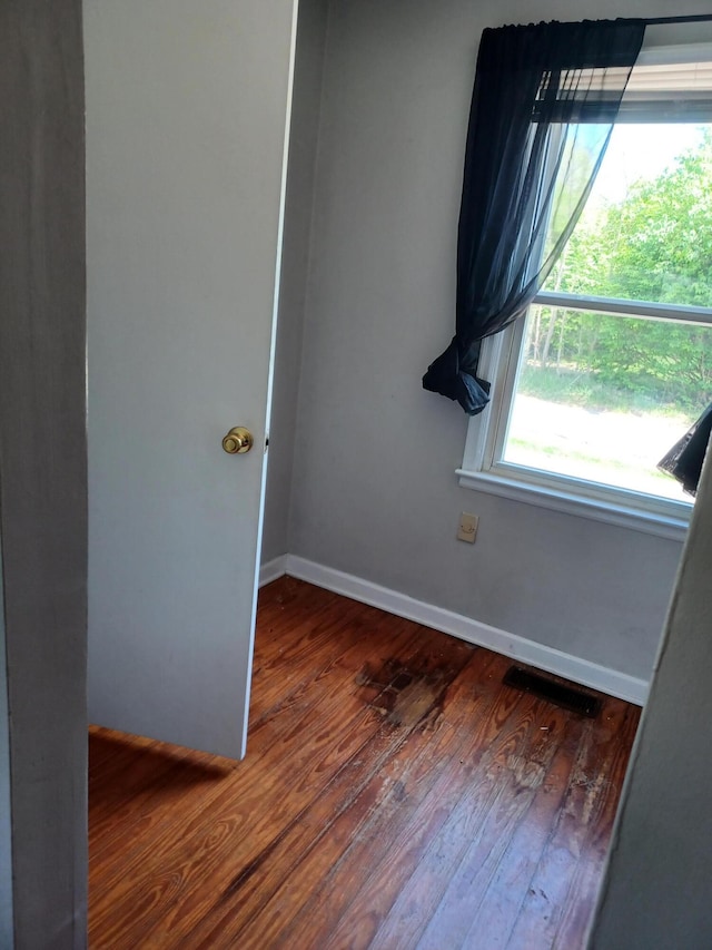 empty room with baseboards, wood finished floors, and visible vents