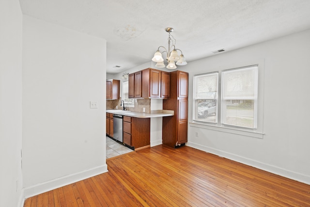 kitchen with a sink, baseboards, visible vents, a chandelier, and dishwasher