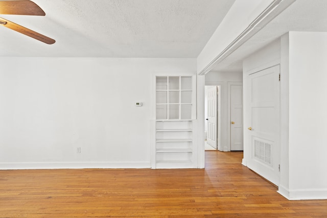 spare room featuring a ceiling fan, a textured ceiling, hardwood / wood-style flooring, baseboards, and visible vents