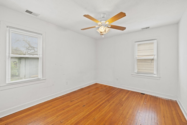 spare room featuring light wood-style floors, visible vents, and a healthy amount of sunlight