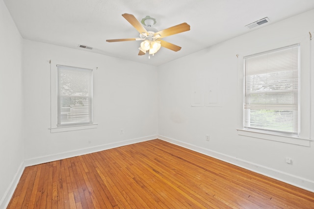 unfurnished room with baseboards, a ceiling fan, visible vents, and light wood-style flooring