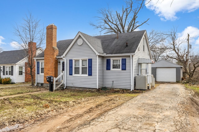 view of front of property featuring a chimney, a shingled roof, driveway, an outdoor structure, and a garage