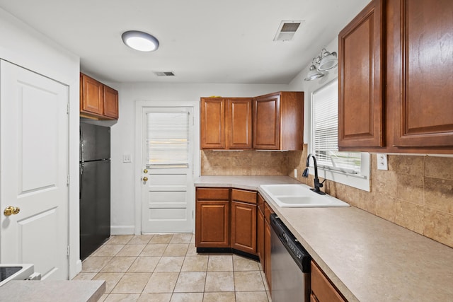kitchen featuring dishwasher, visible vents, a sink, freestanding refrigerator, and tasteful backsplash