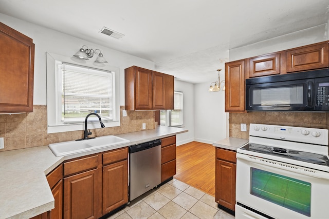 kitchen with visible vents, stainless steel dishwasher, a sink, white range with electric cooktop, and black microwave