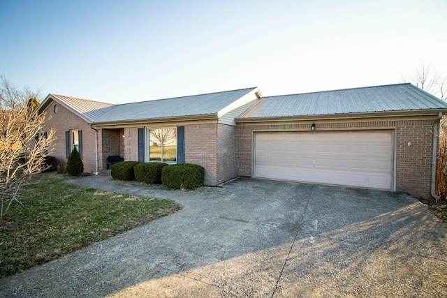 ranch-style house with aphalt driveway, brick siding, a garage, and metal roof