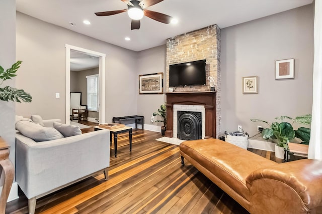 living room featuring a brick fireplace, baseboards, ceiling fan, wood finished floors, and recessed lighting