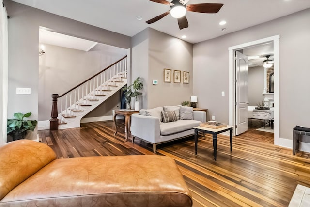 living room featuring hardwood / wood-style floors, baseboards, stairway, and ceiling fan