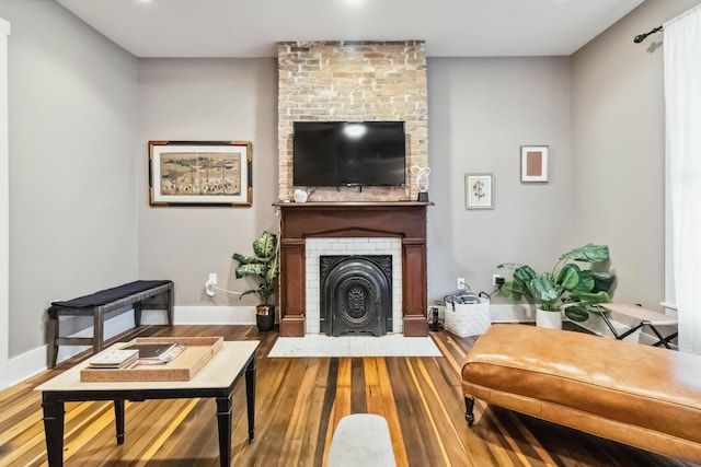 sitting room with baseboards, a fireplace, and wood finished floors