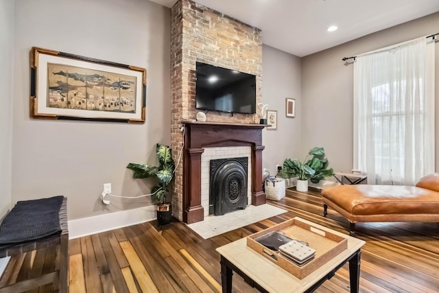 living room featuring hardwood / wood-style floors, baseboards, a fireplace, and recessed lighting
