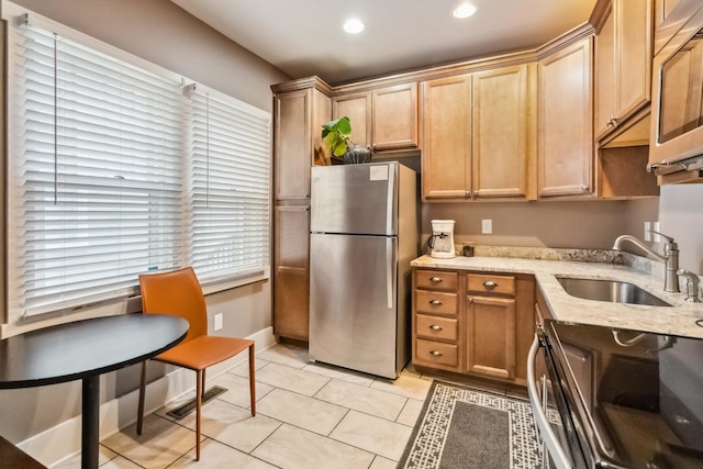 kitchen featuring light tile patterned floors, stainless steel appliances, a sink, light stone counters, and visible vents