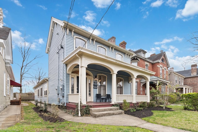 view of front of home featuring a balcony, a porch, and a chimney