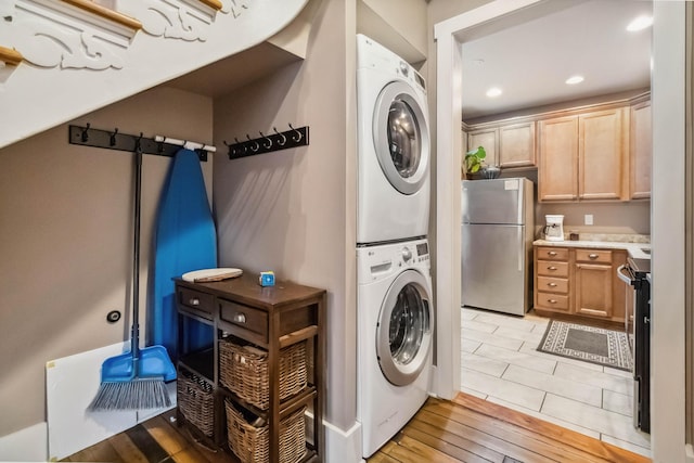 clothes washing area with recessed lighting, stacked washer / drying machine, laundry area, and light wood-style floors