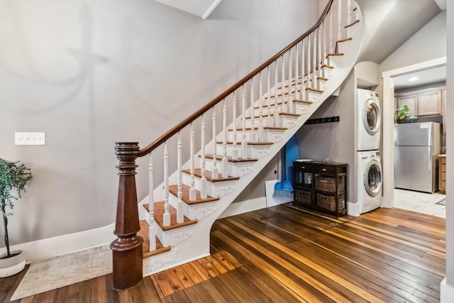 stairs featuring wood-type flooring, a high ceiling, and stacked washer / drying machine
