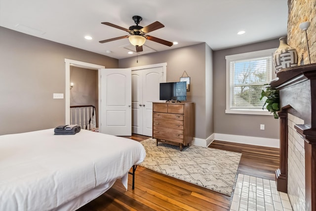 bedroom with recessed lighting, baseboards, a ceiling fan, a fireplace, and wood finished floors
