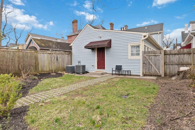 back of house featuring a gate, fence, central AC, and a yard