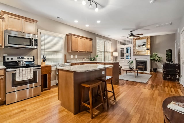 kitchen with visible vents, ceiling fan, appliances with stainless steel finishes, light wood-style floors, and open floor plan