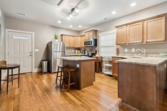 kitchen with a sink, a breakfast bar area, light wood-style flooring, stainless steel appliances, and visible vents