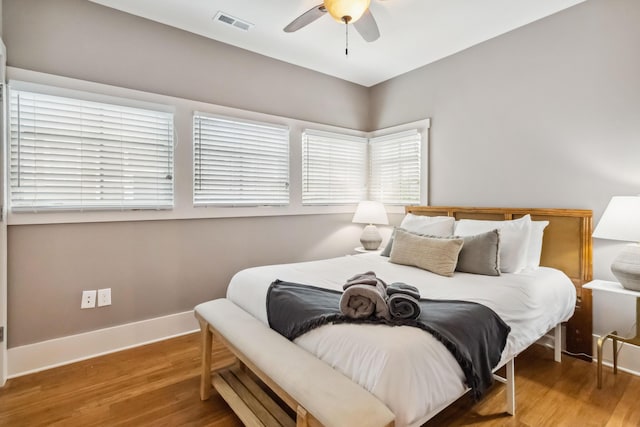 bedroom featuring baseboards, visible vents, wood finished floors, and a ceiling fan