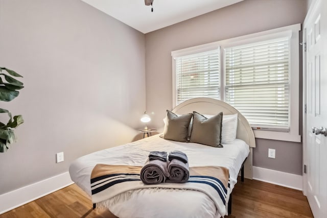 bedroom with a ceiling fan, baseboards, and wood finished floors