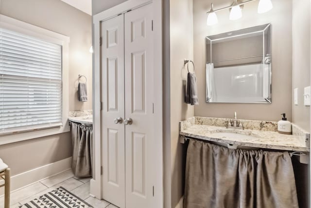 full bath with vanity, baseboards, and a closet