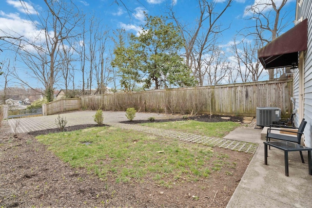 view of yard with a fenced backyard, central AC, and a patio