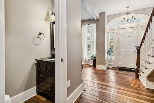 entrance foyer with baseboards, stairs, dark wood-style floors, and a notable chandelier