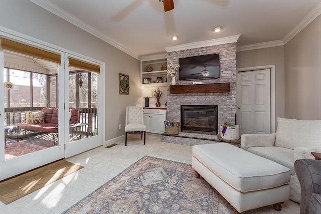 living area featuring crown molding, a brick fireplace, carpet floors, and ceiling fan