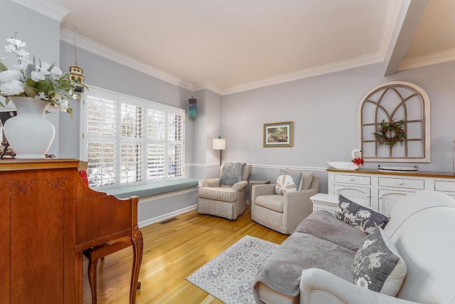 living room with light wood finished floors, visible vents, baseboards, and ornamental molding