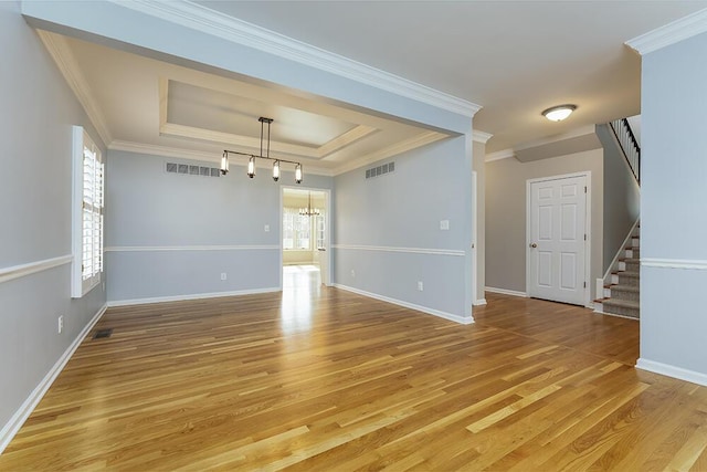 spare room featuring visible vents, a chandelier, stairs, light wood-style flooring, and a raised ceiling