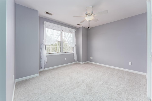 carpeted spare room with a ceiling fan, visible vents, and baseboards