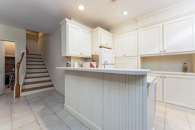 kitchen with freestanding refrigerator, recessed lighting, a peninsula, a breakfast bar area, and light countertops