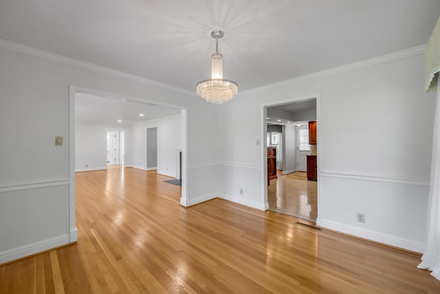 spare room with light wood-type flooring, an inviting chandelier, and crown molding