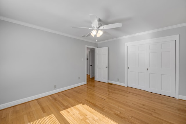 unfurnished bedroom featuring a ceiling fan, a closet, light wood-style floors, crown molding, and baseboards