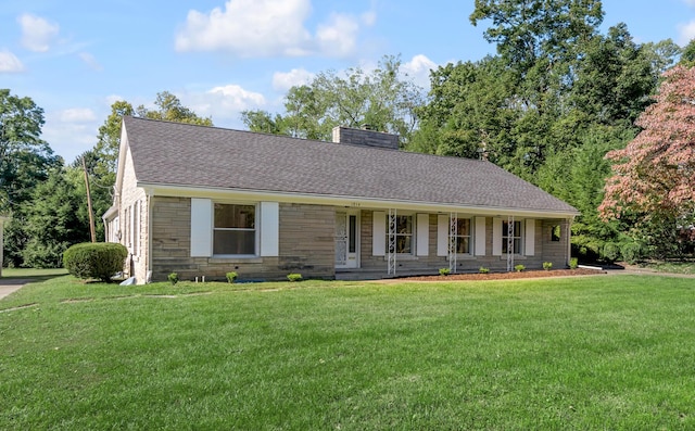 ranch-style home featuring a front yard, a chimney, stone siding, and a shingled roof