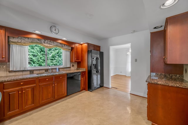 kitchen featuring decorative backsplash, black appliances, dark stone countertops, and a sink